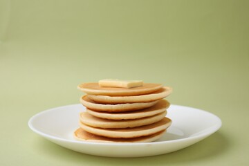 Delicious pancakes with butter on olive color background, closeup