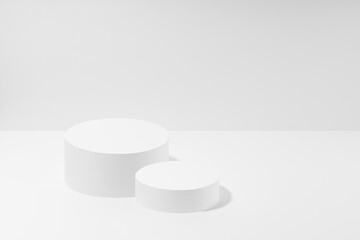 White abstract stage mockup with two white round podiums for cosmetic products in hard light on white background. Scene for presentation cosmetic products, gifts, goods, advertising, design, sale.