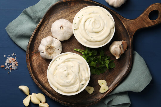 Tasty sauce with garlic and parsley on blue wooden table, flat lay