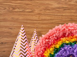 Two festive colored hats and a pinata rainbow on a wooden background. Birthday party and moment of happiness.