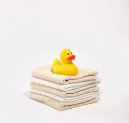 A yellow rubber duck sits on a large number of freshly laundered shower towels. Freshly washed laundry.