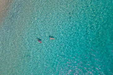 aerial drone view from above at people swimming in the ocean at the Samed Island in Thailand, with a turqouse colored ocean and a white tropical beach view at Koh Samt Thailand