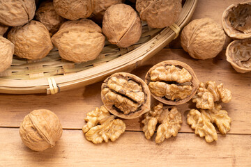 Walnuts kernels in wooden basket on wooden table.