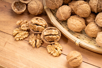 Walnuts kernels in wooden basket on wooden table.