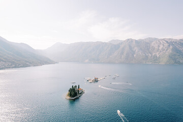Boats sail along the Bay of Kotor past the island of St. George and Gospa od Skrpjela. Montenegro. Drone