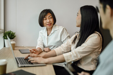 Shot of senior business woman talking or explaining marketing strategy to younger colleagues.