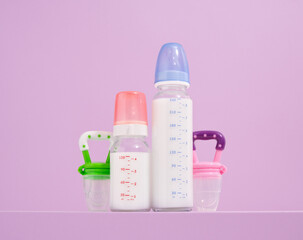 Two plastic milk bottles and pacifiers. Baby care and necessary accessories.