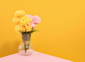 An elegant glass vase with bright flowers on the table. Copy space for text.
