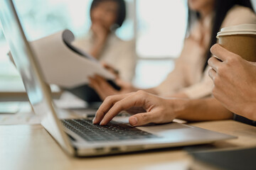 Close up female employee hand typing on laptop while sitting at meeting table.