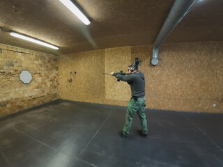 A man shoots a rifle at a target at a shooting range.