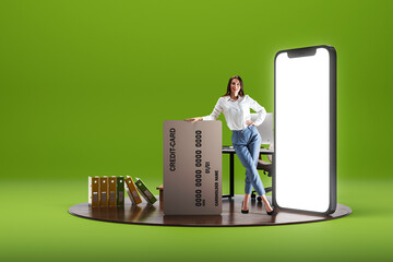 Smiling young woman standing with big credit card near giant 3D model of mobile phone with empty screen over green background. Online shopping - obrazy, fototapety, plakaty
