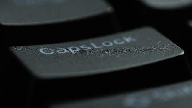 Keyboard button CAPSLOCK. Macro shot of finger pressing CAPSLOCK button