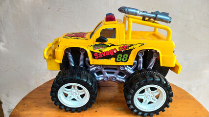 Photo of a yellow radio controlled offroad sports car racing toy car isolated on a wooden base