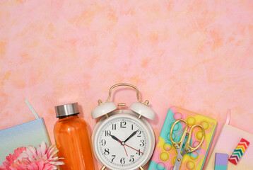 Vintage white alarm clock, pencil case, orange water shaker, scissors, erasers. Flat lay, copy...