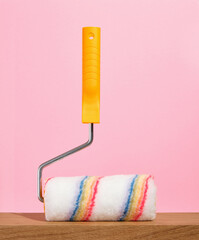 Paint roller on a pink background. Home improvement and construction tools. Renovation concept.
