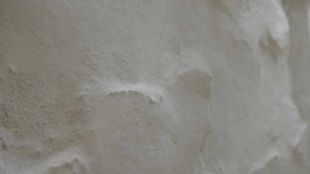 Close-up wall uneven roughly whitewashed white color, flat, textured wall, slow motion