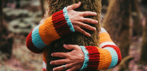 Woman hands bonding hugging tree trunk in the nature woods forest. Wearing colorful sweater. Concept of love nature healthy lifestyle. Environment and trees protection. Outdoor leisure activity people - obrazy, fototapety, plakaty