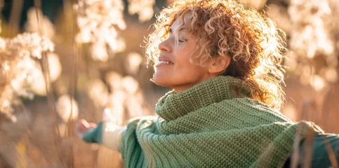 Fototapeten One beauty woman with happy and idyllic expression on face opening arm and enjoying sunset light in the field in scenic outdoor leisure activity. People loving life and healthy lifestyle concept. Life © simona