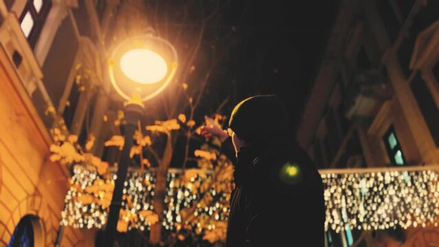 Lonely man pointing at a cozy lamp at night in Holidays time at winter.