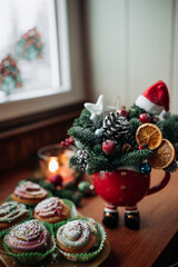 Christmas cupcakes and beautiful Christmas bouquet in a bowl on the table by the window. 