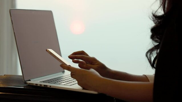 Businesswoman using smartphone for online shopping, scanning qr code on laptop to transfer or pay money without cash at home. Use of technology in the daily life of modern people.