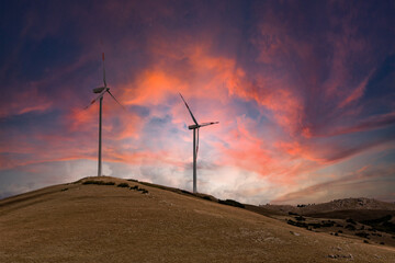 Obraz premium Scenery mountain in winter with a wind farm at sunset Wind turbines for green economy and technology are the only solution to protect the planet from climate change and global warming natural industry