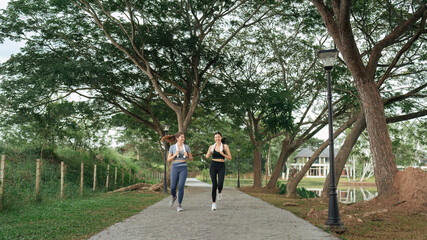 Obraz premium Two happy women going for sunrise running. Women in track suits running at park