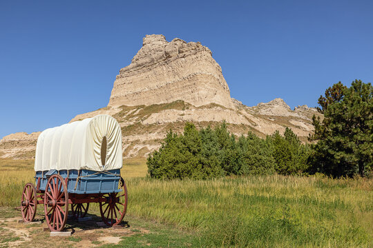 Wagon on display along the Oregon Trail at the entrance of the Mitchell Pass in the vicinity of Sotts Bluff National Monument with Eagle Rock on the right