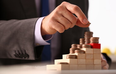 Hand businessman putting pin money financial pyramid tower. Future needs loan education or mortgage...