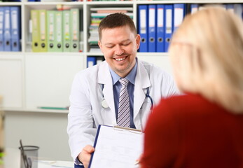 Handsome smiling male doctor talk with patient about his history list. Physical exam er anamnesis communication disease prevention ward round 911 prescribe remedy healthy lifestyle concept - obrazy, fototapety, plakaty