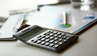 Silver calculator with gray keyboard is lying on desk graph and pen office setting. Calculation of family expenses social income population freelance irs situation growth research concept
