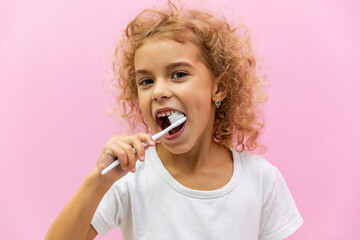 Happy smiling child kid girl brushing teeth with toothbrush on pink background. Health care, dental...