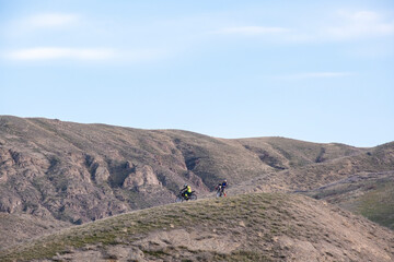 A group of comrades helps a fallen motorcyclist. A motorcyclist rides on a wheelie. Mountain, cross-country motorcycle on the rear wheel. Extreme sports in the desert.