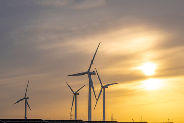 Obraz premium Technological landscape, wind turbines and solar panels at sunset. The power plant is at sunset. Wind turbines and solar panels on a sunset background.