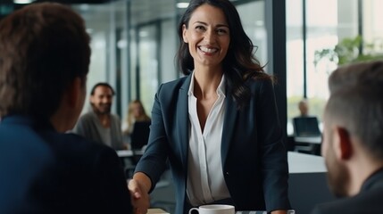 Happy mid aged business woman manager handshaking greeting client in office. Smiling female executive making successful deal with partner shaking hand at work standing at meeting table
