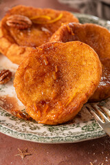 Traditional Christmas french toast or rabanadas with sugar syrup, cinnamon and pecan nuts on a rustic kitchen counter at Christmas time.