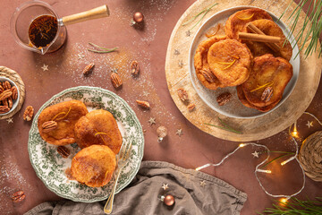 Traditional Christmas french toast or rabanadas with sugar syrup, cinnamon and pecan nuts on a rustic kitchen counter at Christmas time. - obrazy, fototapety, plakaty