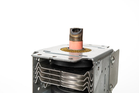 Magnetron on a white background. Magnetron with a burnt metal cap. Magnetron from a microwave oven, the cause of sparks and smoke from a microwave oven.