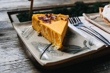 Pumpkin Pie Slice with rose petals on Decorative Ceramic Plate. A delicious slice of pumpkin pie topped with garnish, served on a botanical-themed ceramic plate.