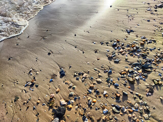 Yellow sand, pebbles and a transparent wave as a background, texture. Abstract pattern, place for text, copy space