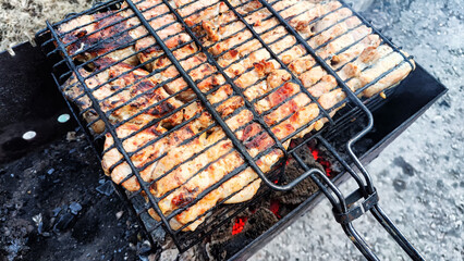 Pieces of shish kebab on an iron grill over the coals over the grill. Delicious fried meat