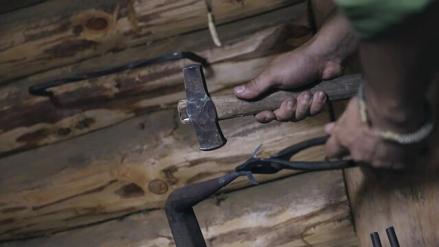 A blacksmith armorer produces a spearhead of an uncharacteristic shape. He strikes at the workpiece