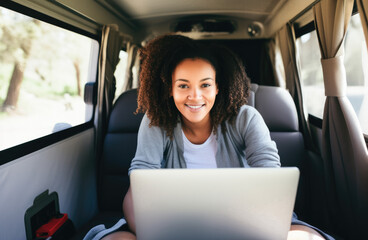 Independent woman sitting inside a camper van in using a laptop. Living and working inside camper van vehicle in travel and digital nomad free lifestyle. 