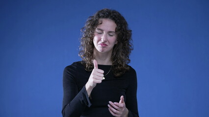 Woman clapping hands congratulating viewer standing on blue background looking at camera signalling...