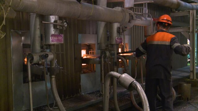 A stoker cleans a burning boiler at a thermal power plant
