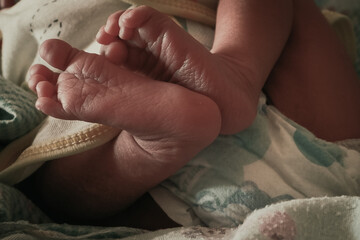 Close-up of unrecognizable cute baby shaking feet while lying in bed, innocence concept, a pair of sleeping baby feet, tiny baby feet