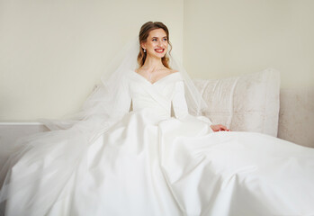 Beautiful bride in white wedding dress posing in her room at home