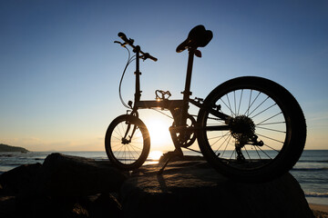 A folding bike on sunrise seaside rocks