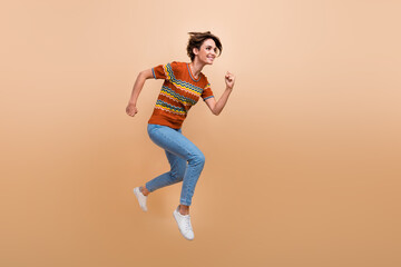Fototapeta na wymiar Full size profile photo of energetic pretty girl jump run empty space ad isolated on beige color background