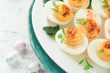 Easter stuffed eggs. Traditional Easter brunch or dinner with stuffed eggs with paprika, carrot cake bars and chocolate nest cakes with glazed eggs. Easter meal dishes with holday decorations Top view